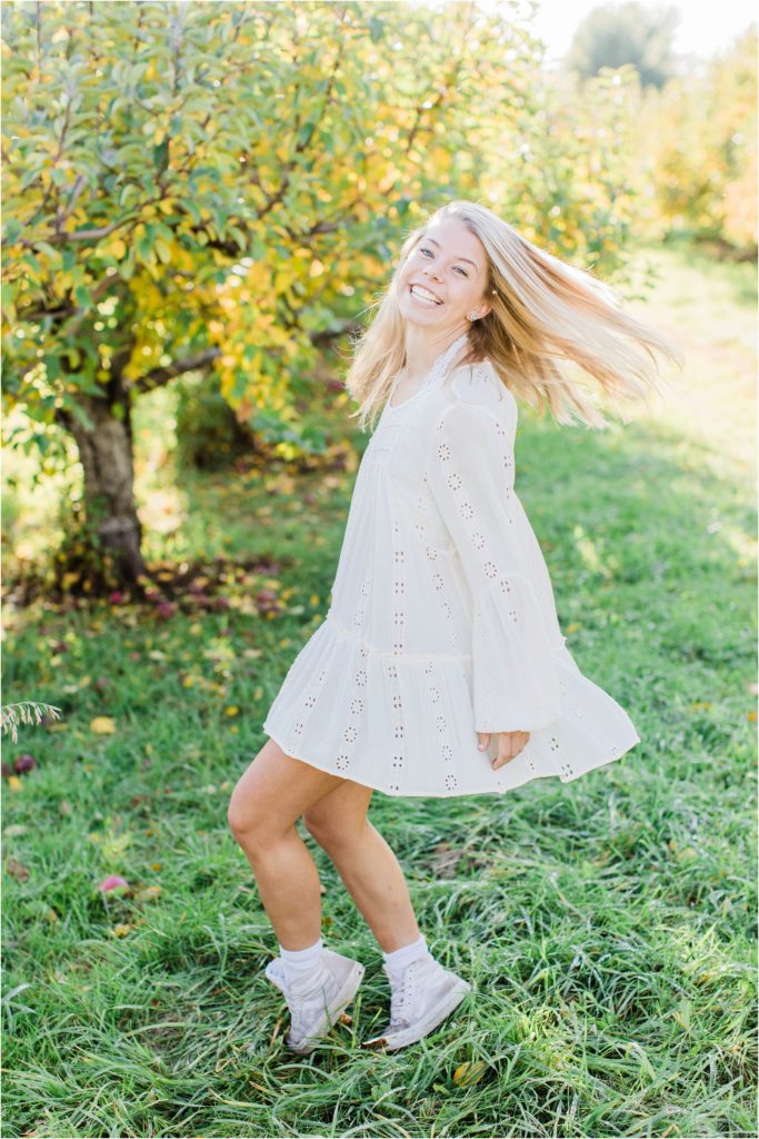 Senior girl twirling in trees in white dress