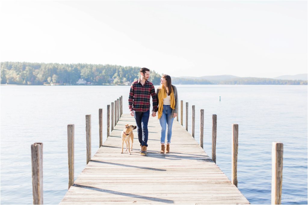 couple walking on dock with dog fall engagement photos