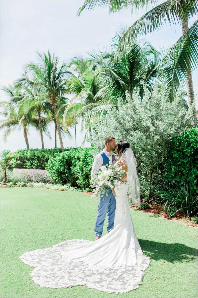 bride and groom standing together under palm trees