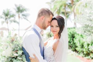 groom nuzzling bride in front of beach