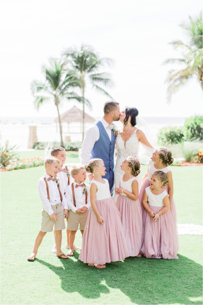 bride and groom kissing in front of grossed out kids