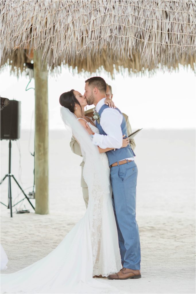 bride and groom first kiss on beach