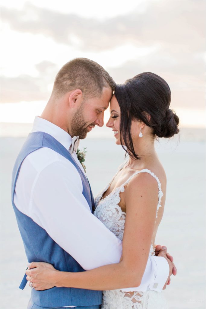 bride and groom standing on beach at sunset on marco island``