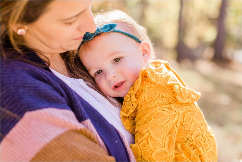 toddler in mustard dress snuggling with mom