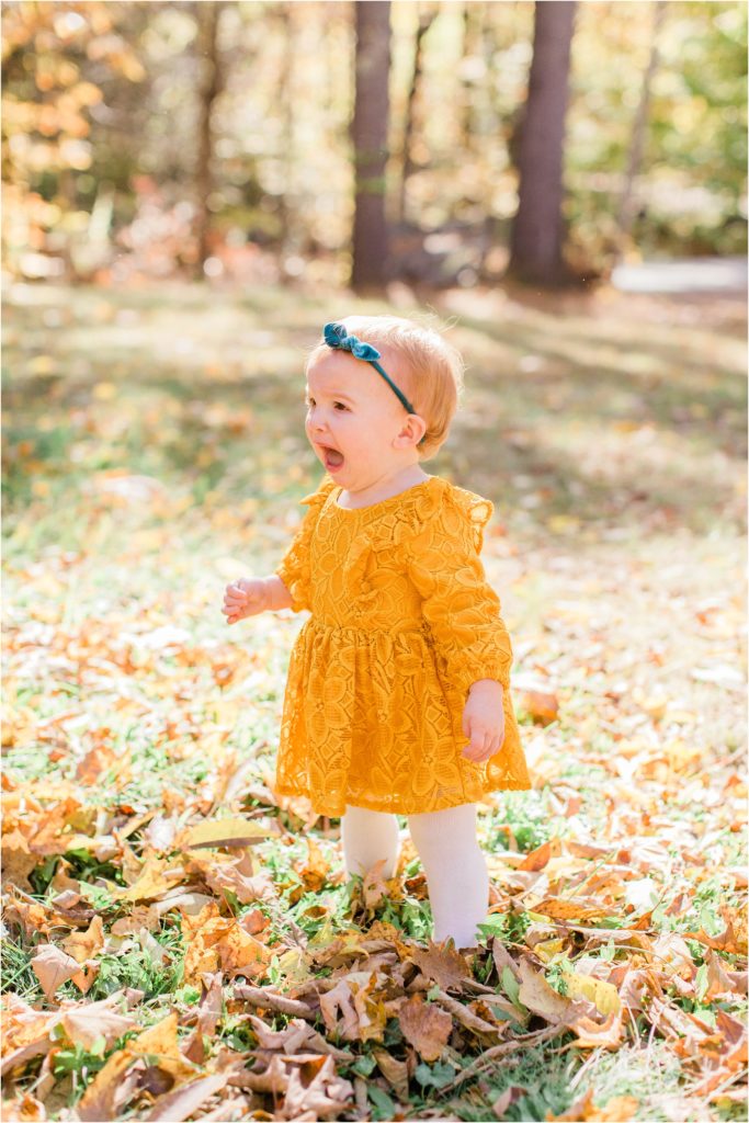 toddler in mustard colored dress standing in yard