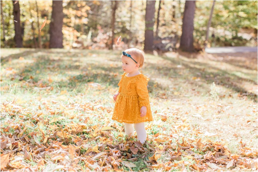 toddler in mustard colored dress standing in yard