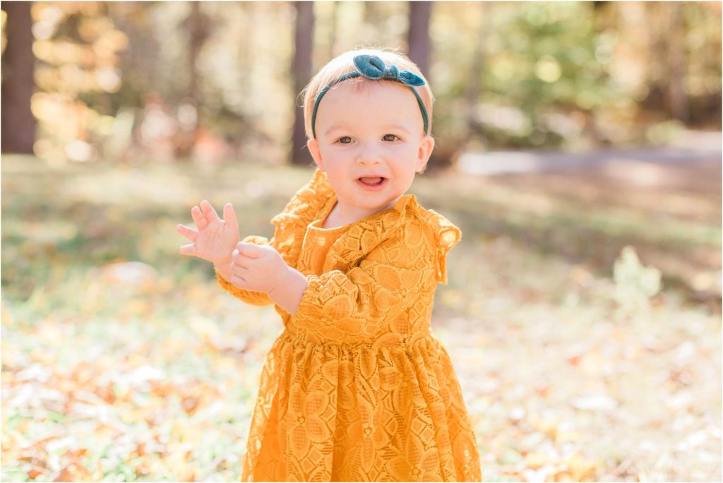 toddler in mustard colored dress standing in yard