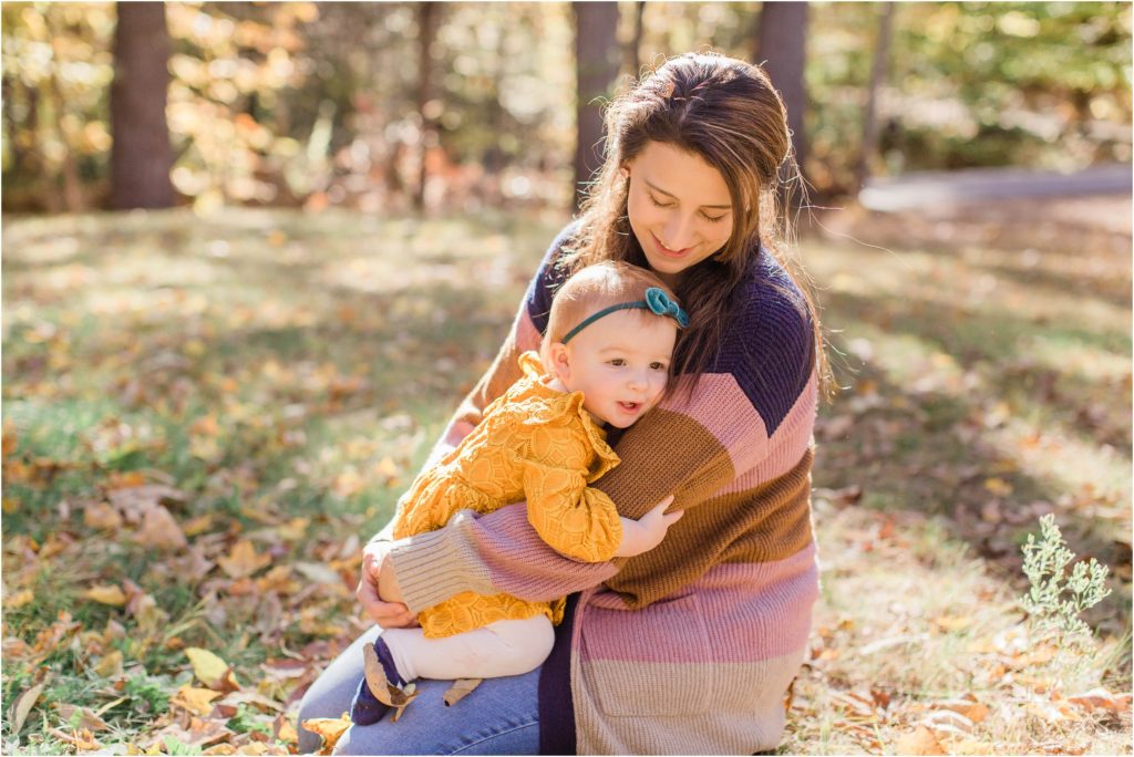 toddler girl in mustard colored dress snuggling with mom