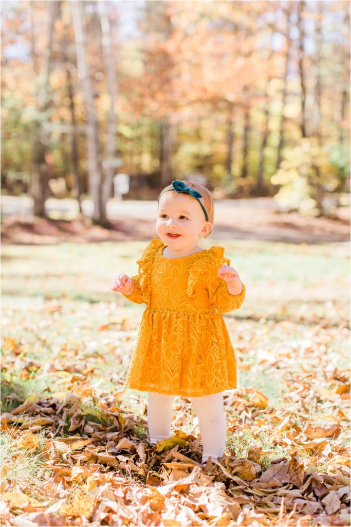 toddler in mustard colored dress standing in yard