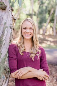 Woman standing against tree smiling