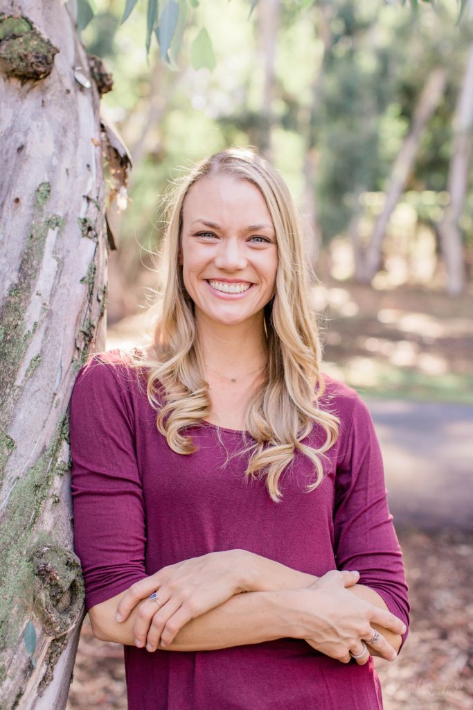 Woman standing against tree smiling