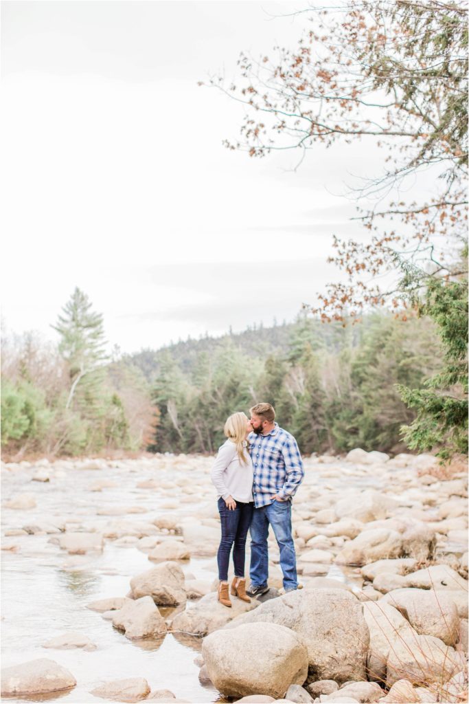 Man and woman kissing standing on rocks in middle of river
