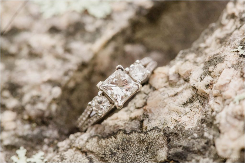 Square cut diamond engagement ring resting on granite rock