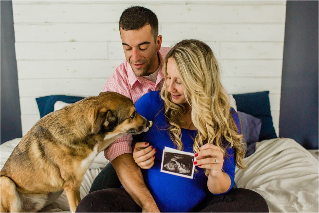 pregnant woman and man sitting on bed with dog