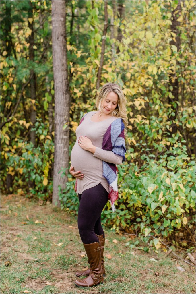 pregnant woman standing in front of autumn leaves