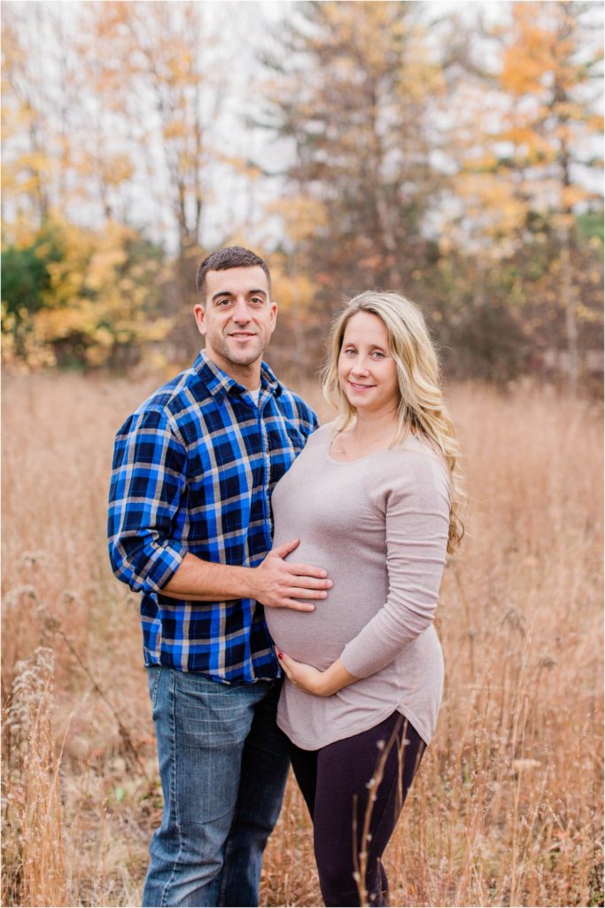 man and pregnant woman standing together in a field