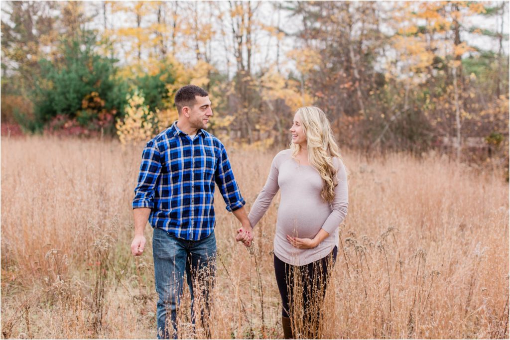 pregnant woman and man walking through field together