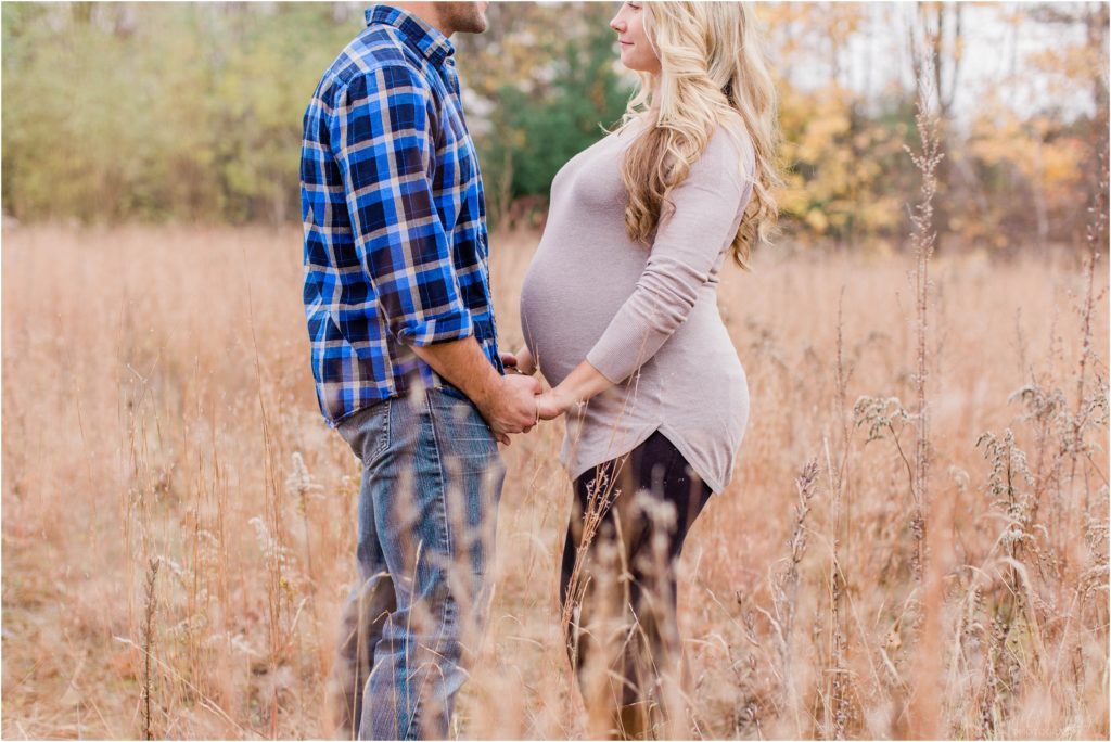 pregnant woman and man holding hands in a field