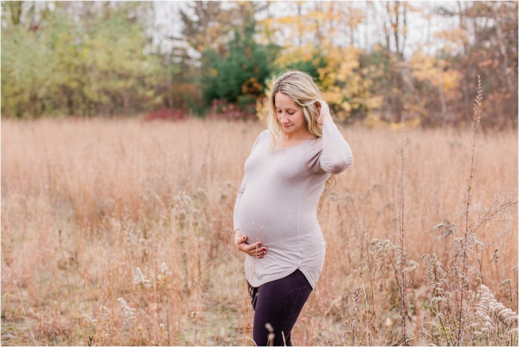 pregnant woman holding her belly standing in a field
