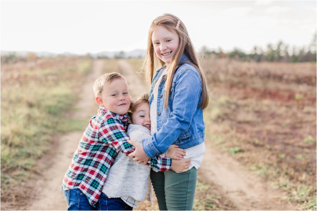 Siblings snuggled together in field