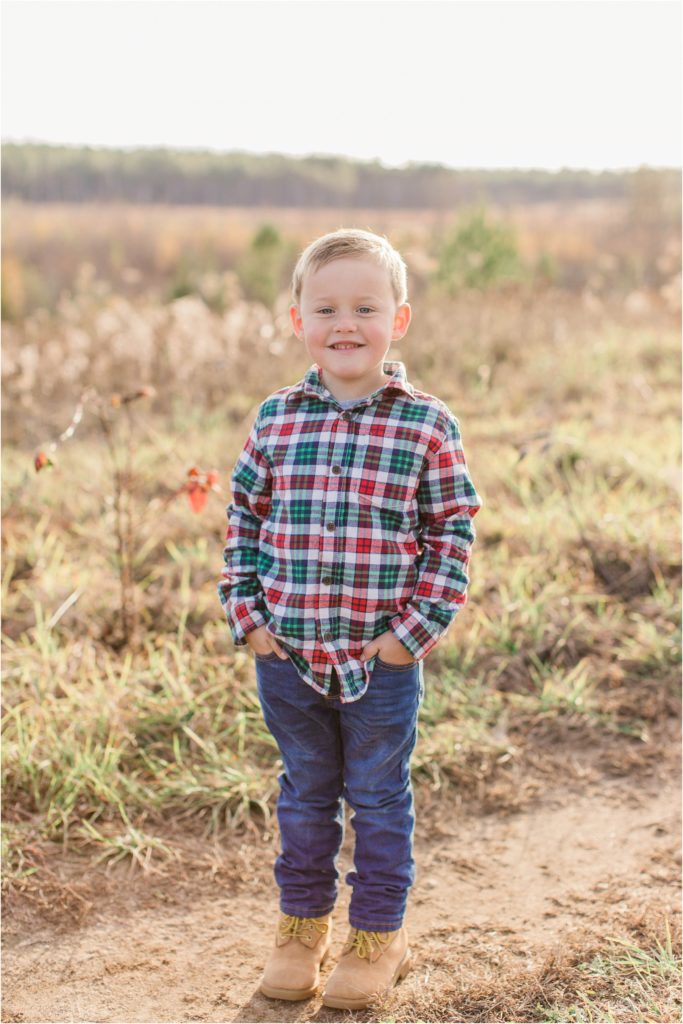 Little boy standing in field in checkered shirt