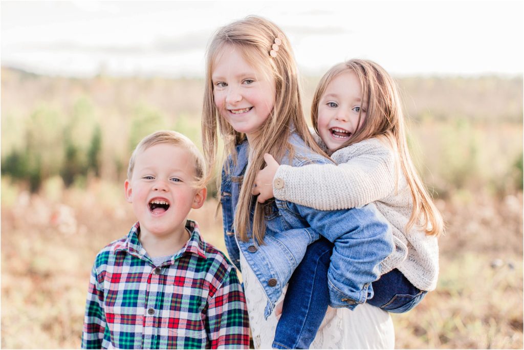 3 siblings standing tougher with older sister holding little sister on her back