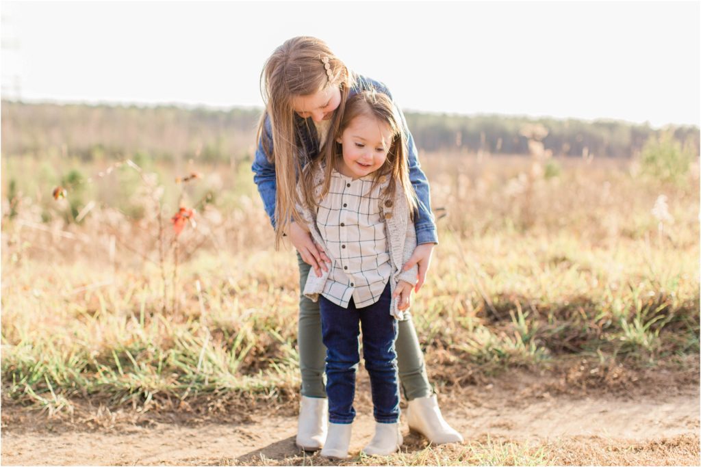 Older sister helping little sister stand for photo