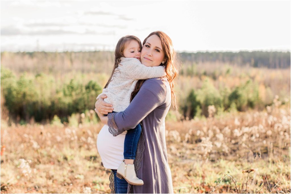 Little girl sitting on mom's pregnant belly