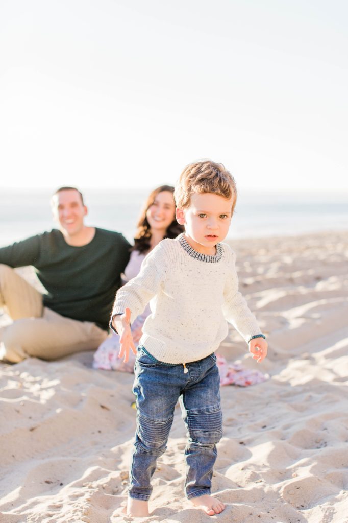 Little boy running from parents on beach