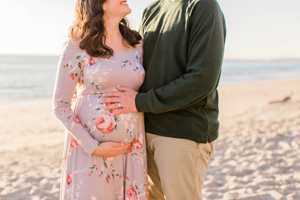 Couple holding baby belly on the beach
