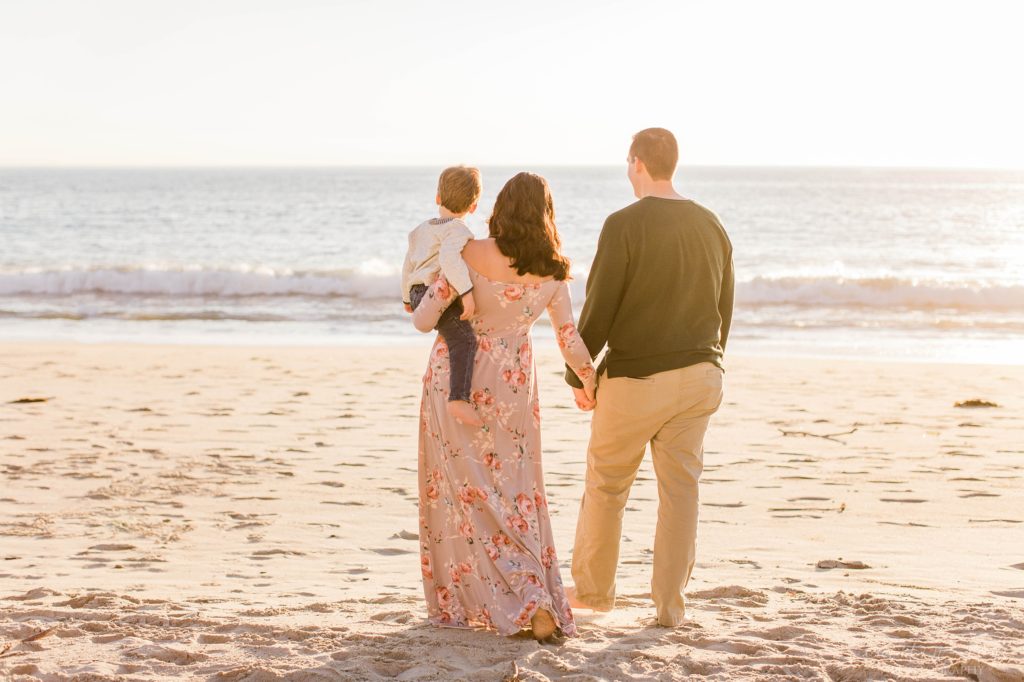 Family walking towards the ocean at sunset