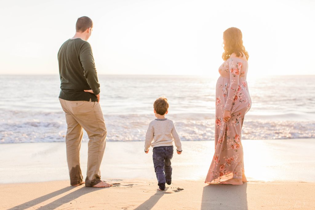 Family standing on the beach at sunset