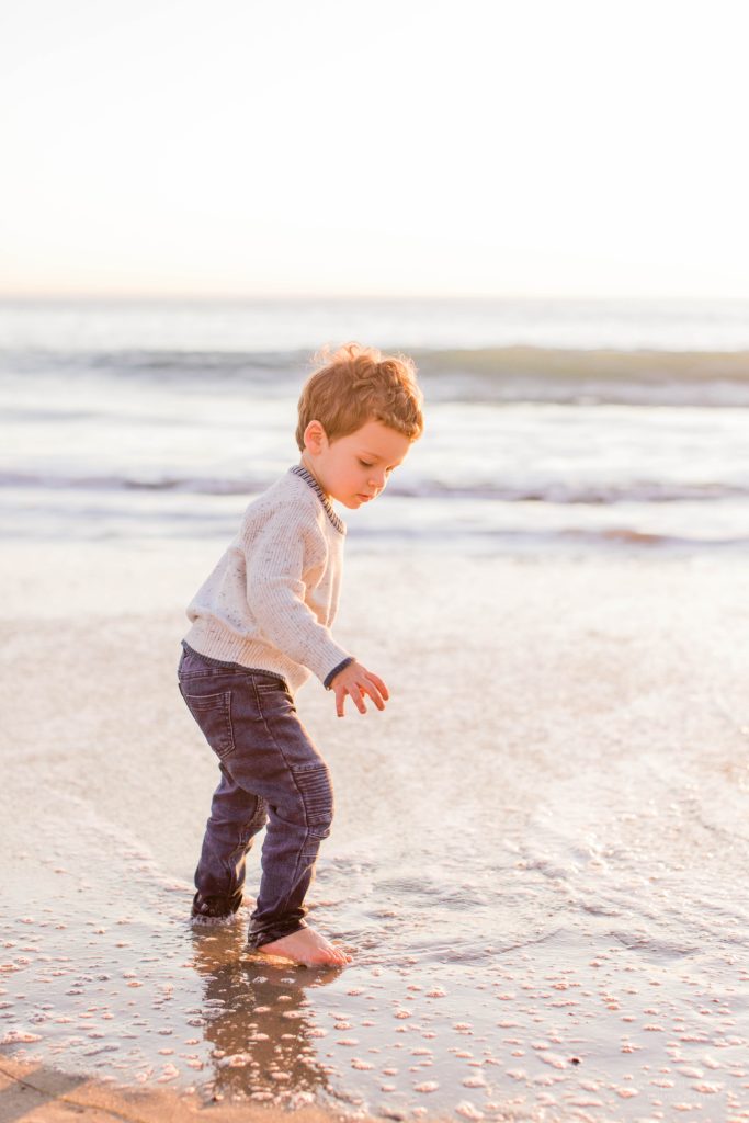 Little boy playing on the beach at sunset