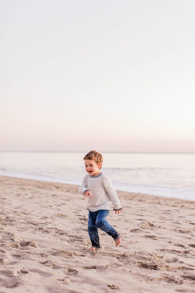 Little boy running from ocean at sunset
