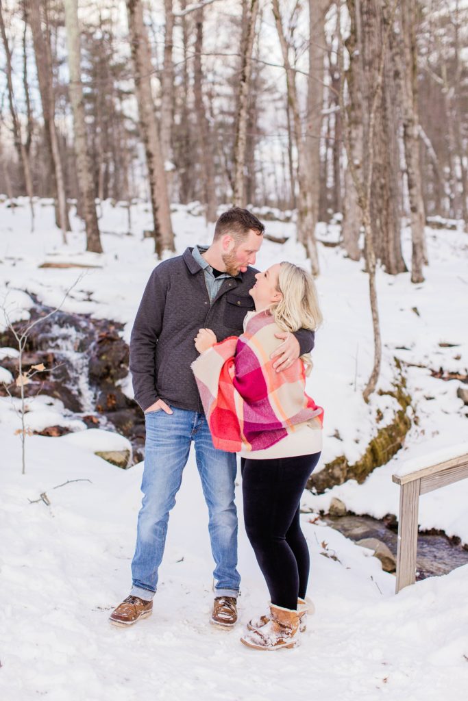 Couple standing together by a brook in the snow