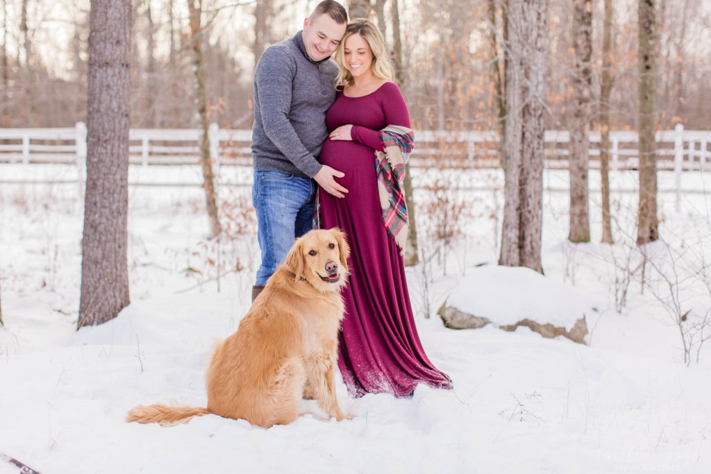 Pregnant woman and husband looking at golden retreiver