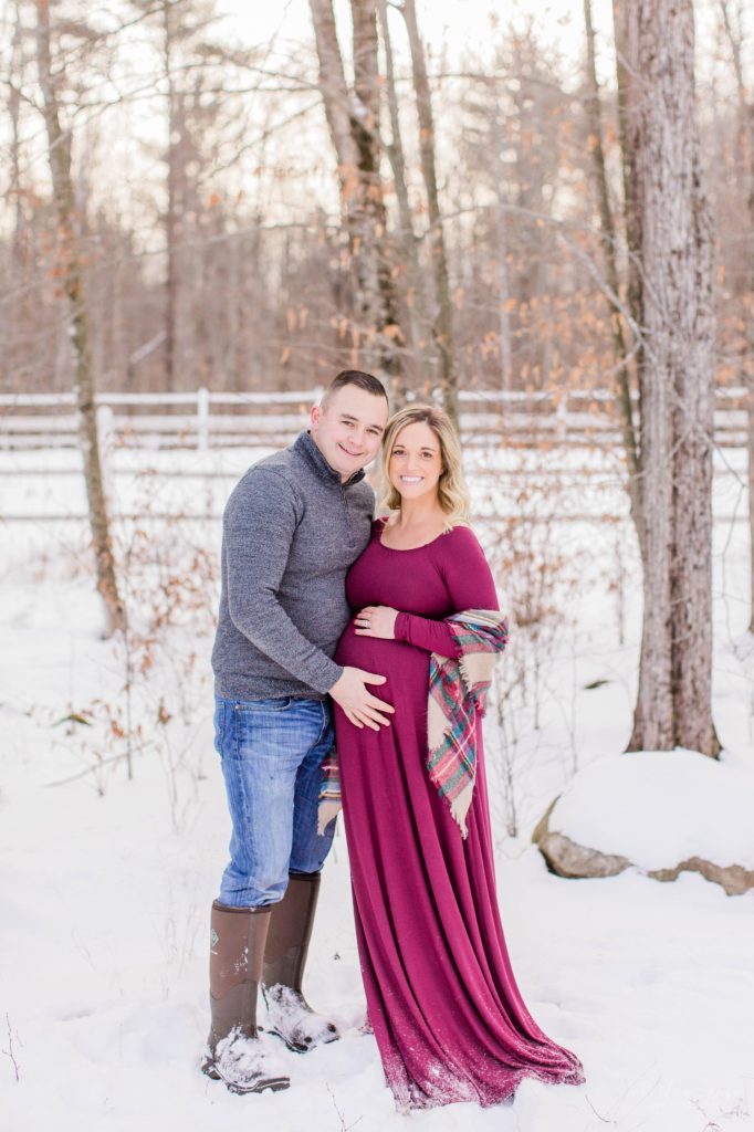 Pregnant woman and man looking at camera in snowy field