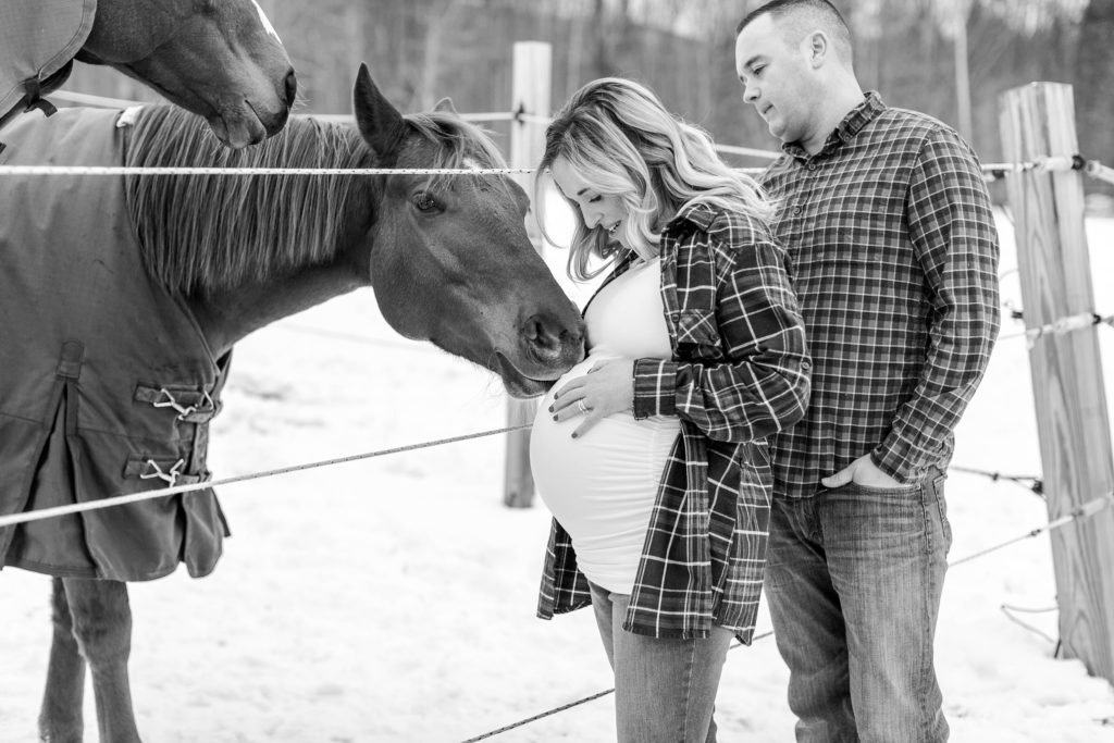 Black and white photo of man and pregnant woman with horses