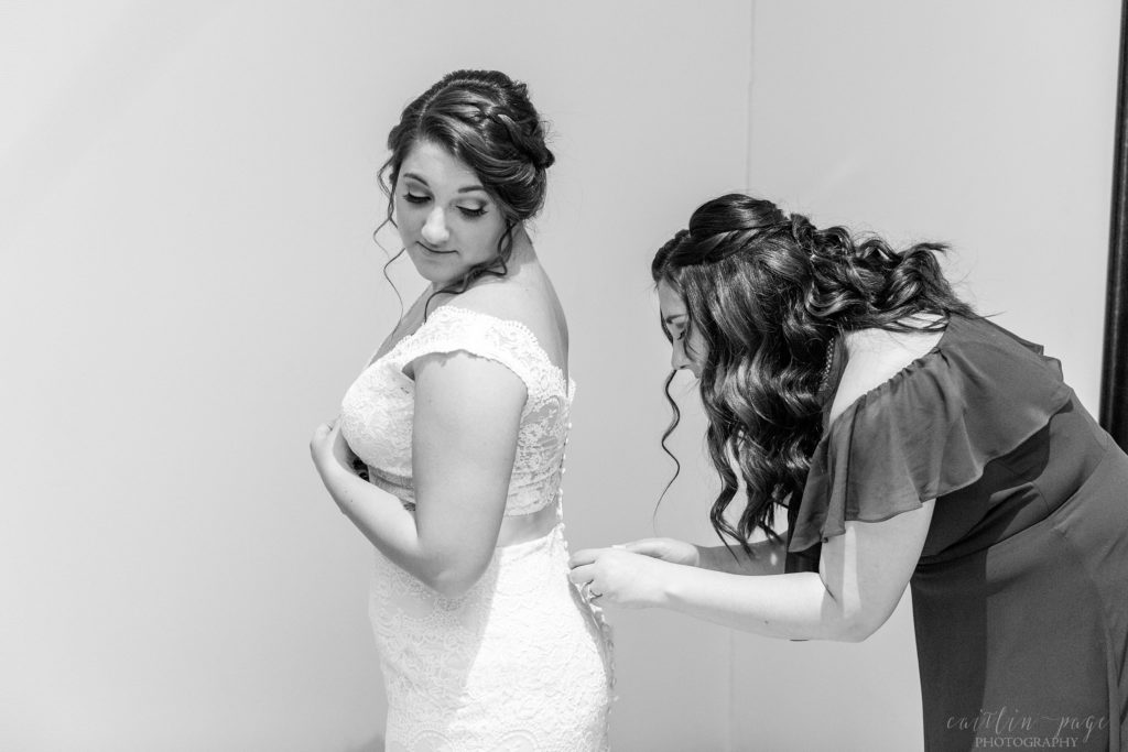 Bride getting buttoned into her dress