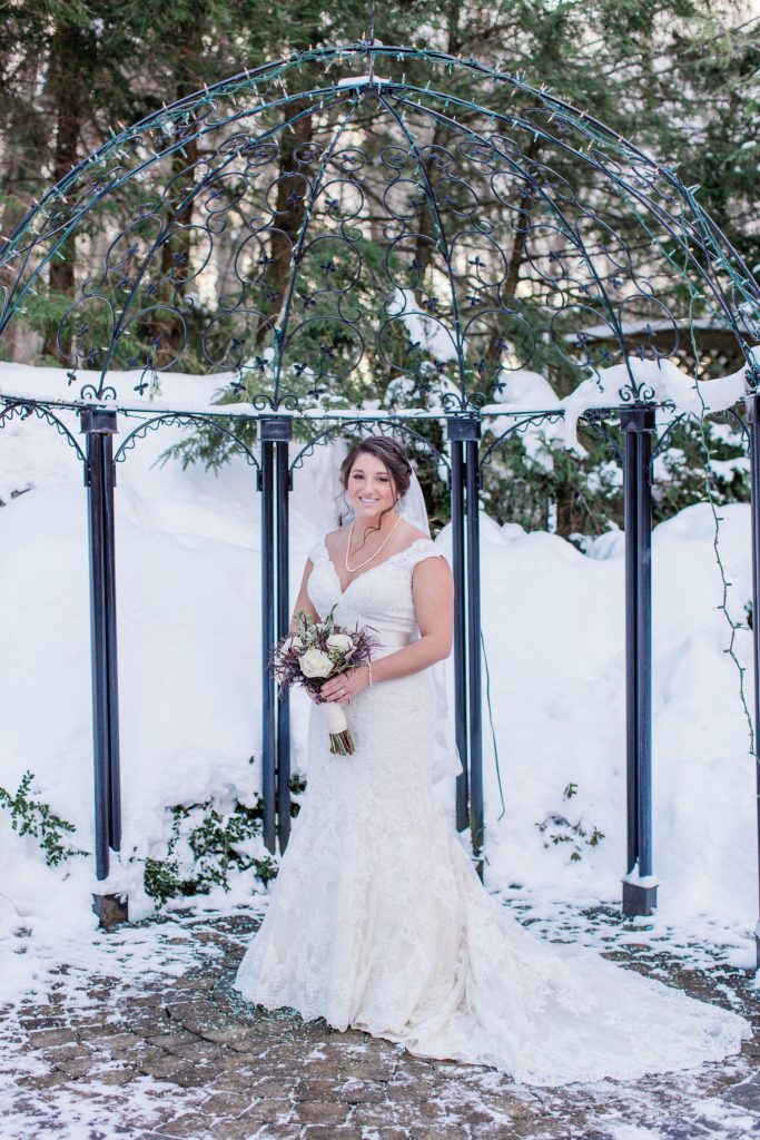 Bride standing out in snow holding her bouquet