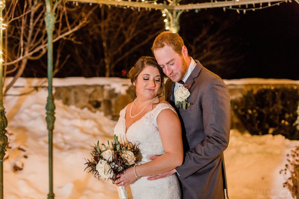 Bride and groom standing under gazebo in the snow