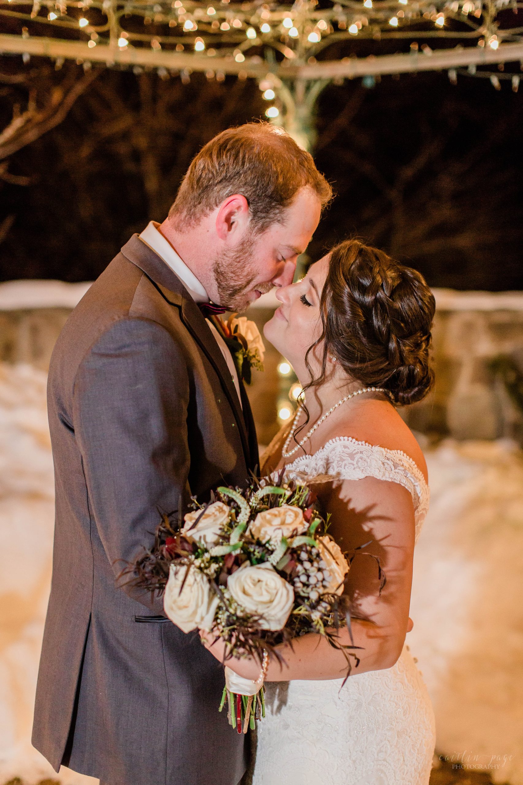 Bride and groom standing under gazebo in the snow