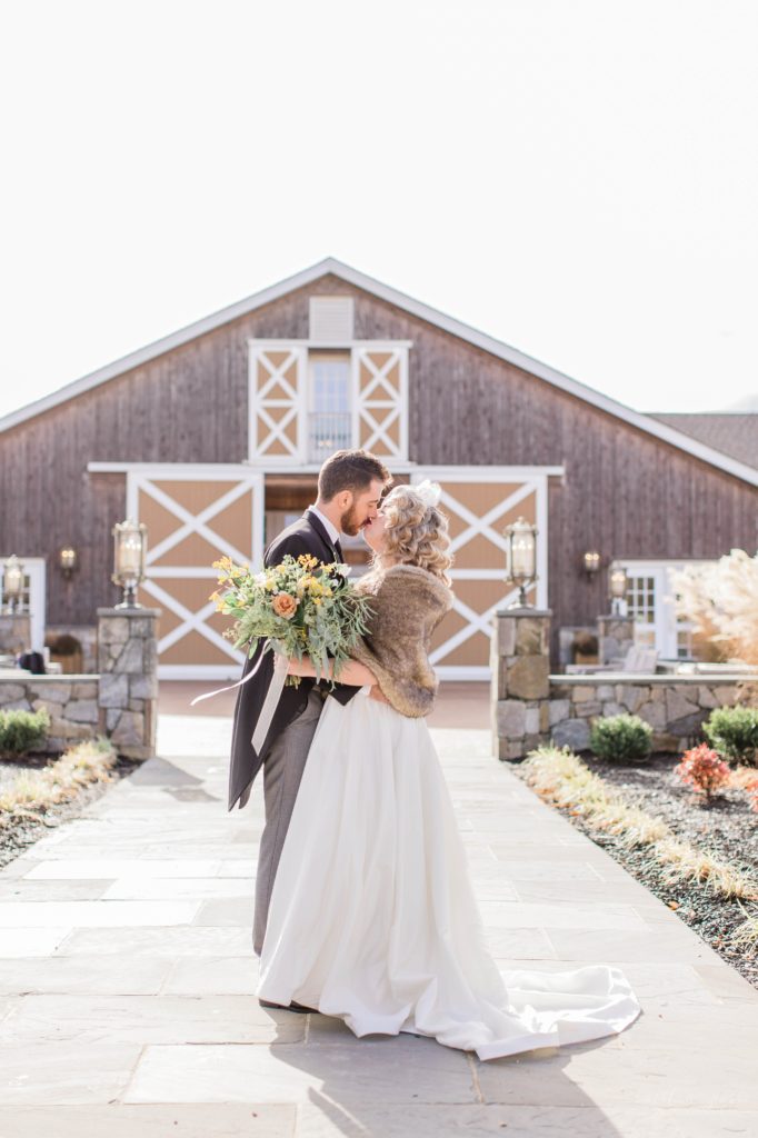 Bride and groom kissing in front of barn at Mount Ida Farm in Charlottesville Virginia
