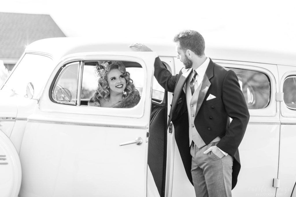 Black and white shot of bride sitting in vintage car with groom looking at her at Mount Ida Farm in Charlottesville Virginia