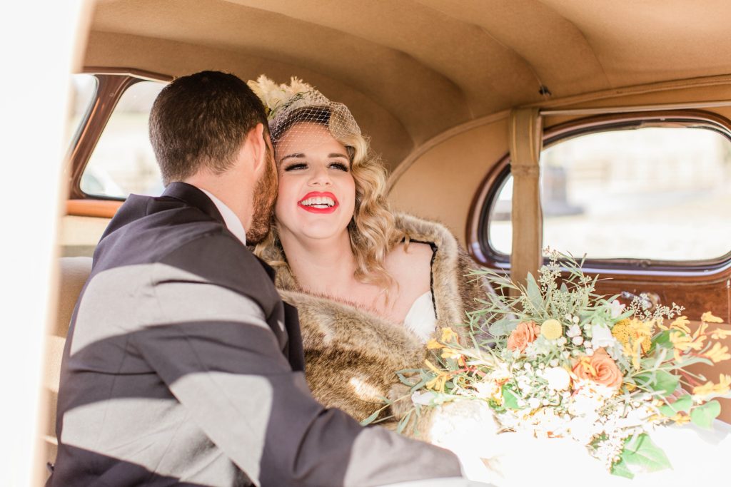 Groom whispering into brides ear in the backseat of vintage car at Mount Ida Farm in Charlottesville Virginia