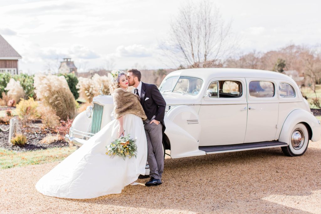 Portrait of brie and groom kissing in front of vintage car at Mount Ida Farm in Charlottesville Virginia