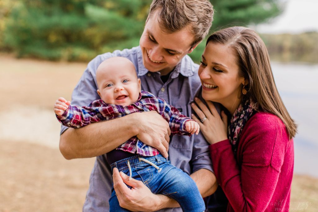 Baby smiling at camera while his dad holds him at Merrimack River in Concord, New Hampshire