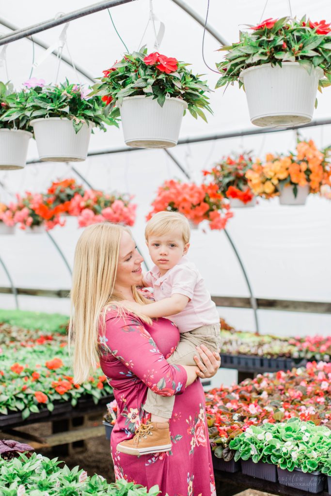 Little boy snuggled in his moms arms in a greenhouse