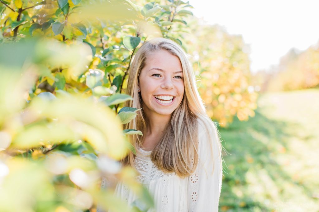 High school senior girl standing in apple orchard in Concord New Hampshire