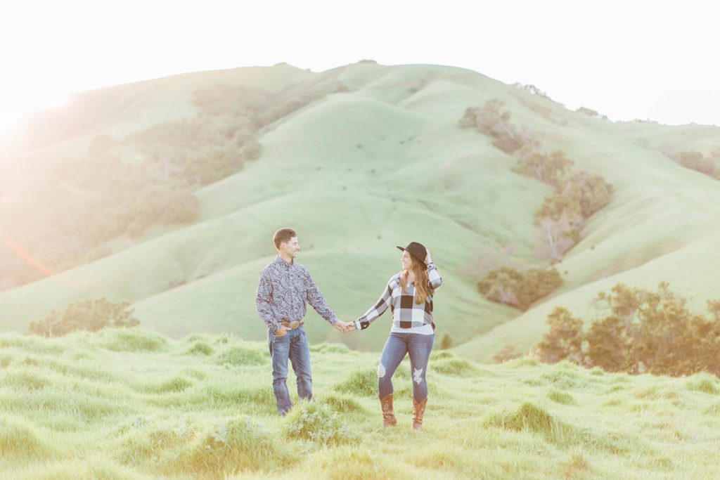 Man and woman standing together in rolling hills at sunset